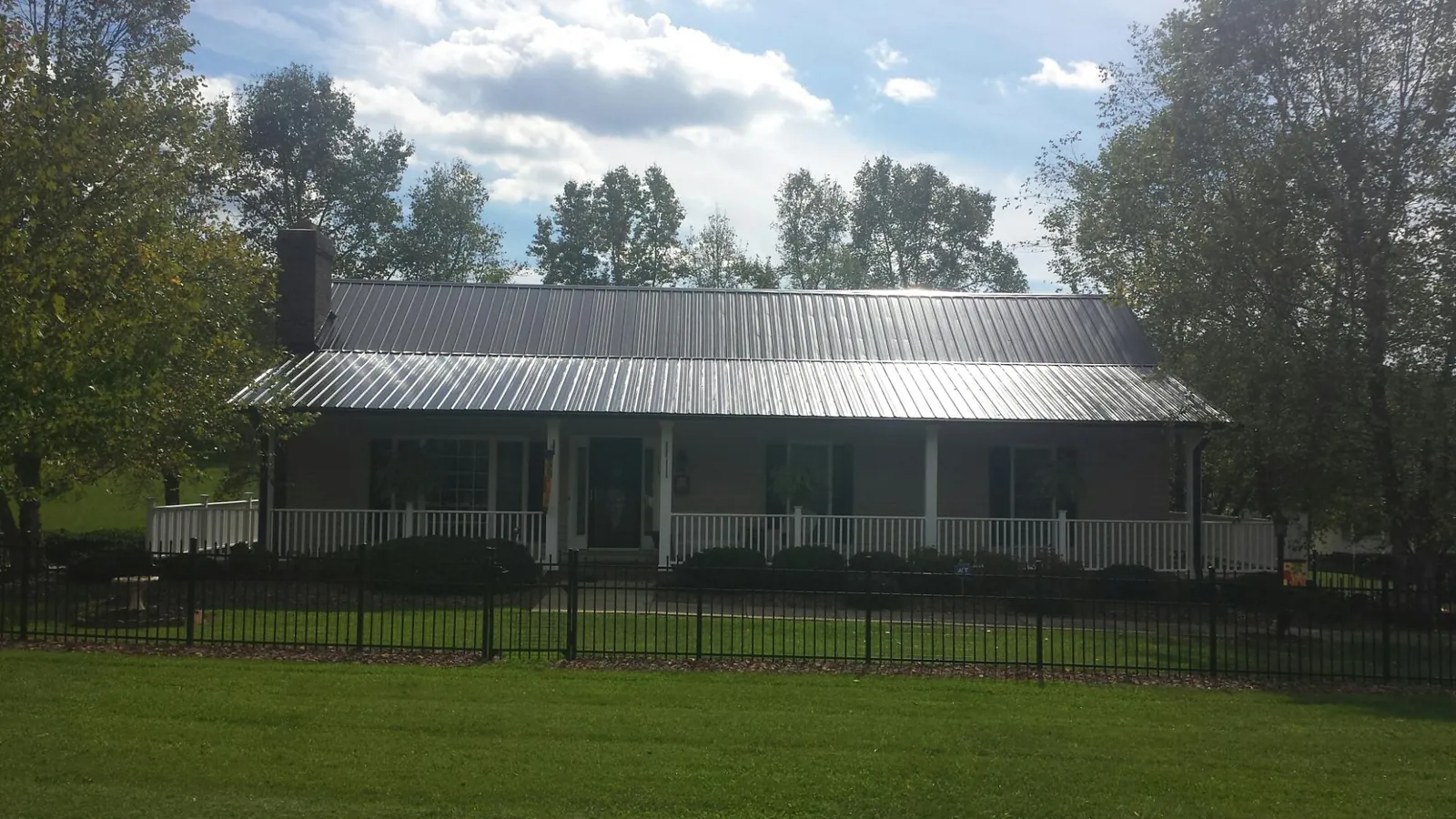 Gray metal roof on a brick ranch with a full width front porch — Gutter Guard Installation work by our crew in Belle Plaine