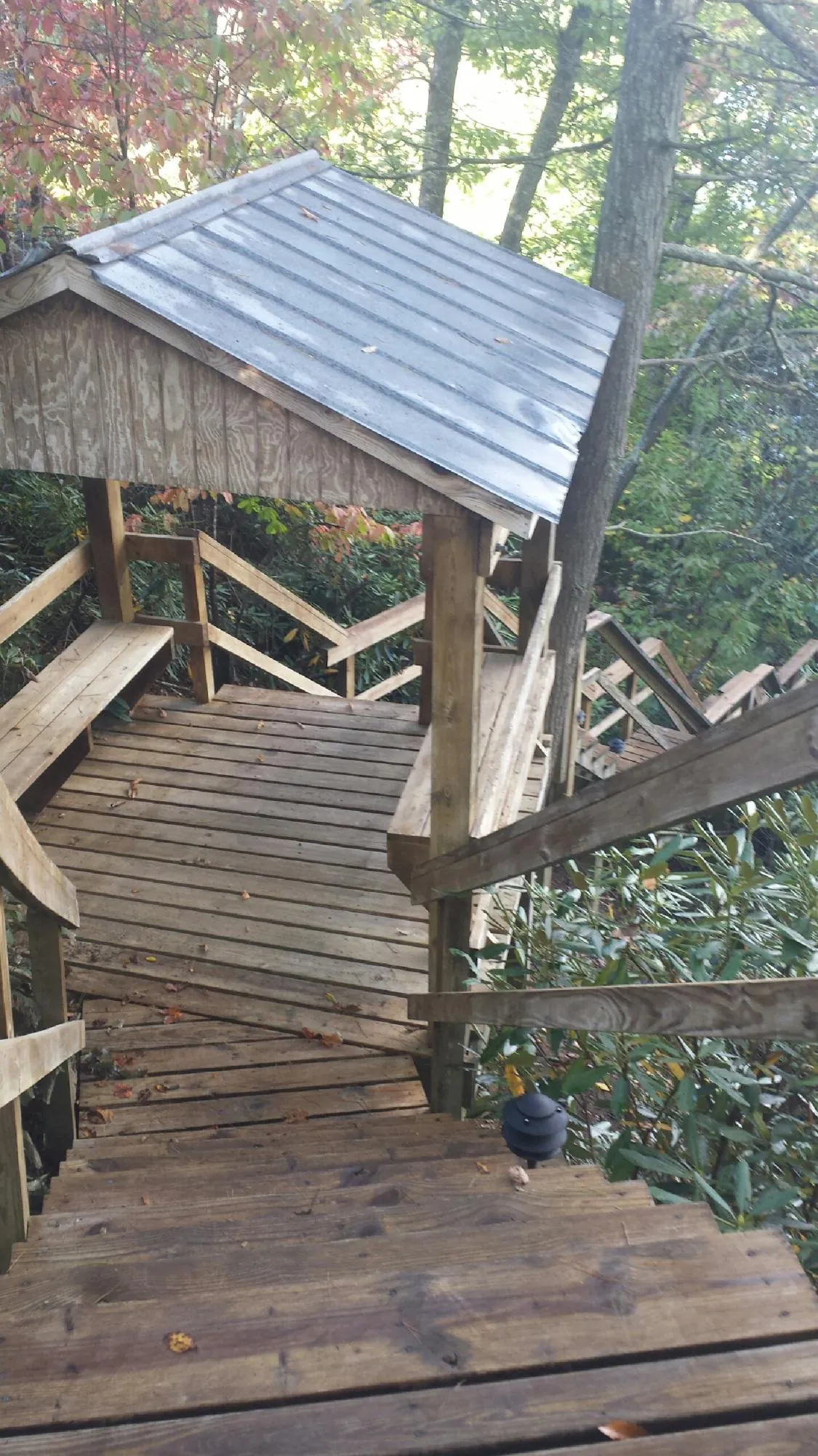 Metal roofed shelter over wooden steps on a wooded walkway — Skylight Repair & Installation work by our crew in Belle Plaine